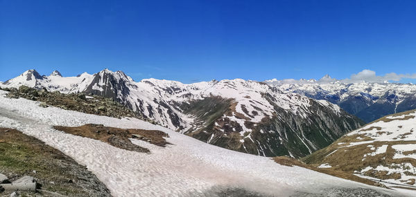 Scenic view of snowcapped mountains against clear blue sky