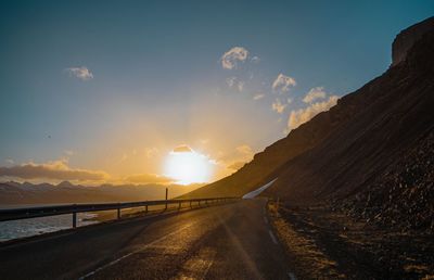 Road amidst mountains against sky during sunset