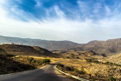 Road leading towards mountains against sky