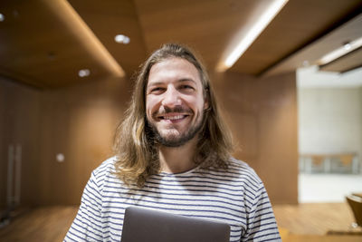 Portrait of laughing man with laptop in university