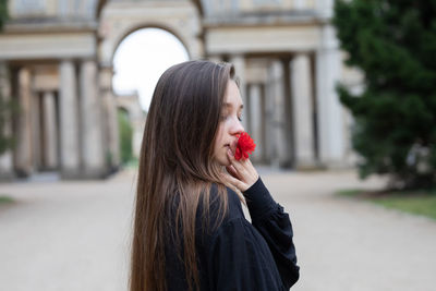 Close-up of woman holding flower standing outdoors