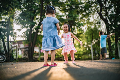 Siblings playing on road by trees