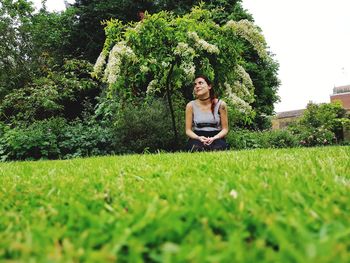 Woman sitting on field against trees