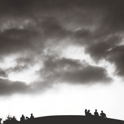 Low angle view of people against cloudy sky