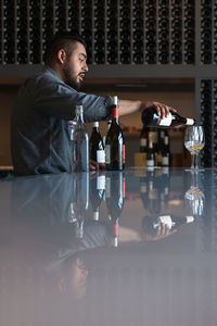 Side view of bartender pouring wine in glasses