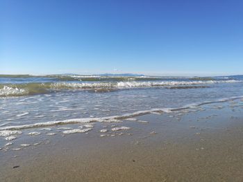 Scenic view of beach against clear blue sky