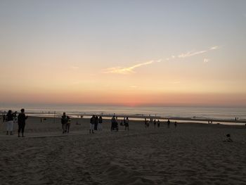 Silhouette people on beach against sky during sunset