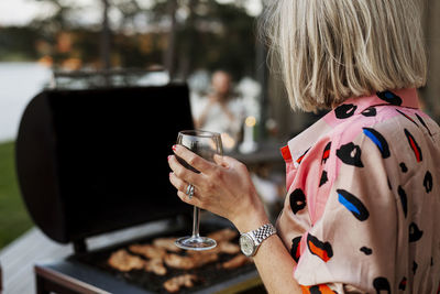 Woman holding wine glass and barbecuing meat