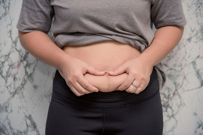 Midsection of woman standing against wall
