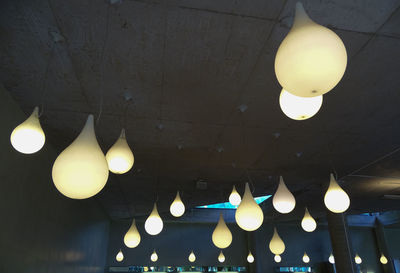 Low angle view of illuminated light bulb hanging on ceiling