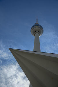 Low angle view of communications tower and building against sky