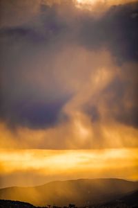 Scenic view of mountains against cloudy sky at sunset