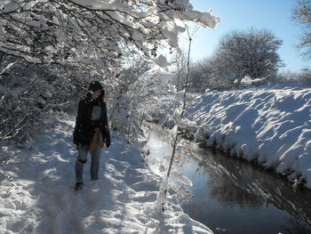 Woman standing by snow covered tree