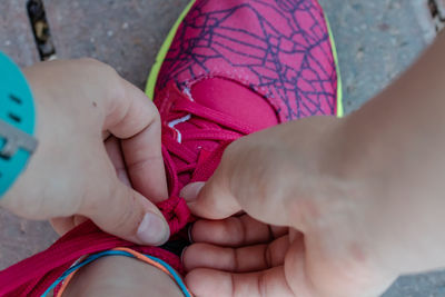 Cropped image of woman tying shoelace on footpath