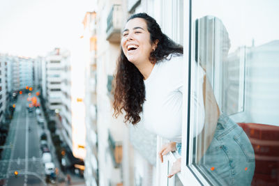 Cheerful woman leaning out of window