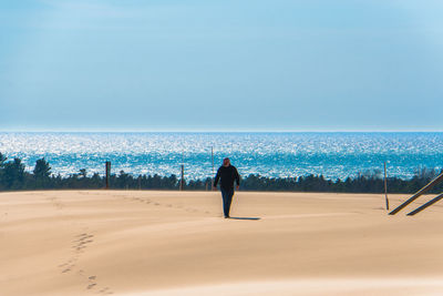 Full length of man walking on sand at beach against sky