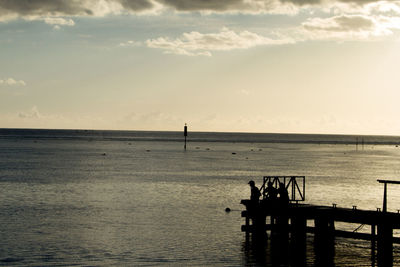 Silhouette pier over sea against sky during sunset