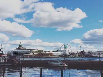 View of buildings by river against cloudy sky