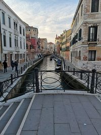 Canal amidst buildings in city against sky
