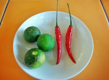 High angle view of red chili pepper and lemons in plate