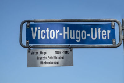 Low angle view of road sign against clear blue sky