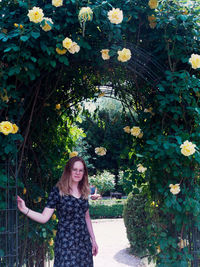 Portrait of a smiling young woman standing by plants