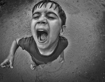 Overhead view of a child with mouth open in the rain