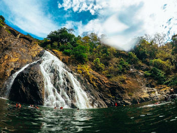 Scenic view of waterfall in forest against sky