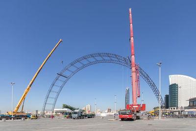 View of cranes against clear blue sky