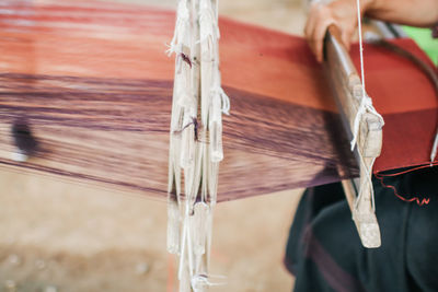 Midsection of woman working on loom in factory