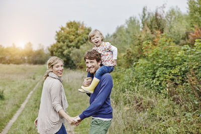 Family on a trip with father carrying daughter on shoulders