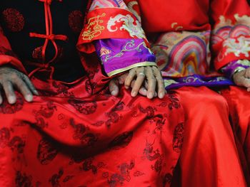 Midsection of senior couple sitting in red traditional clothing