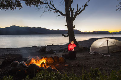 Woman working on laptop at camp at the nahuel huapi lake in patagonia