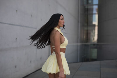 Young woman standing against wall