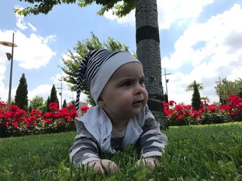 Close-up of cute baby boy lying on grassy field at park