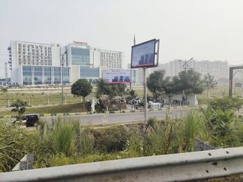 Park by buildings in city against clear sky