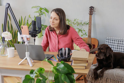 Portrait of young woman with dog sitting at home