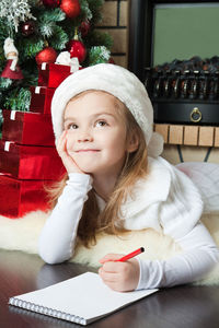 Portrait of cute girl sitting on table at home