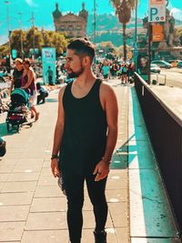Handsome young man standing on footpath in city