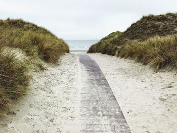 Footpath by sea against sky