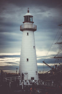 Low angle view of lighthouse by building against sky