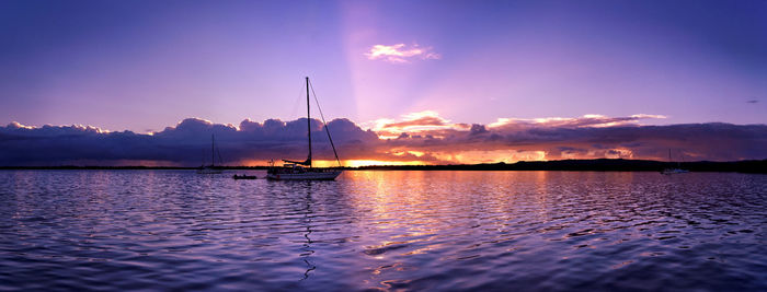 Sailboats in sea against sky during sunset