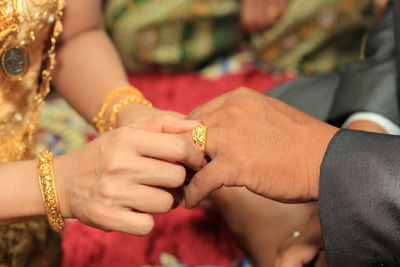 Midsection of bride putting ring in groom finger