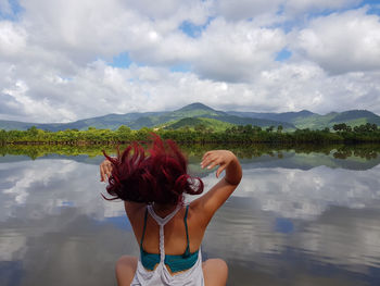 Woman with tousled hair sitting against lake