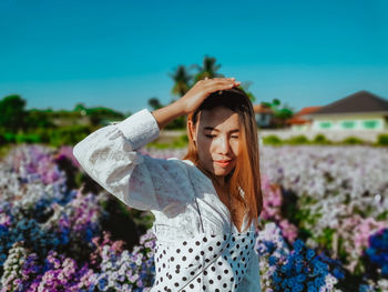 Young woman with arms raised standing outdoors