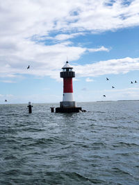 Lighthouse on sea against sky