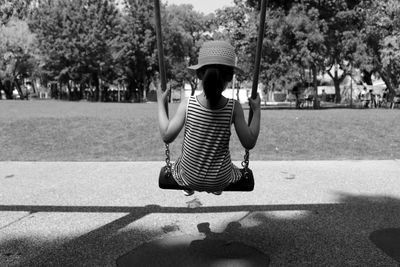 Rear view of girl sitting on swing at playground