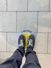 Low section of man standing on tiled floor