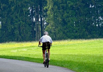 Rear view of man riding bicycle on road