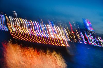 Light trails against blue sky at night